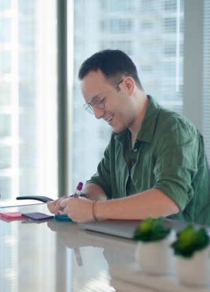 Male creative director jotting down notes on sticky pad while smiling